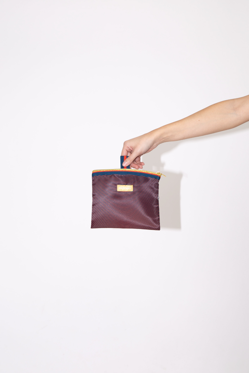 Pochette Isabella Blue de Multitudes en azul y naranja, con tejido reciclado efecto seda, cremallera dorada y lazo lateral, fabricada en Italia.