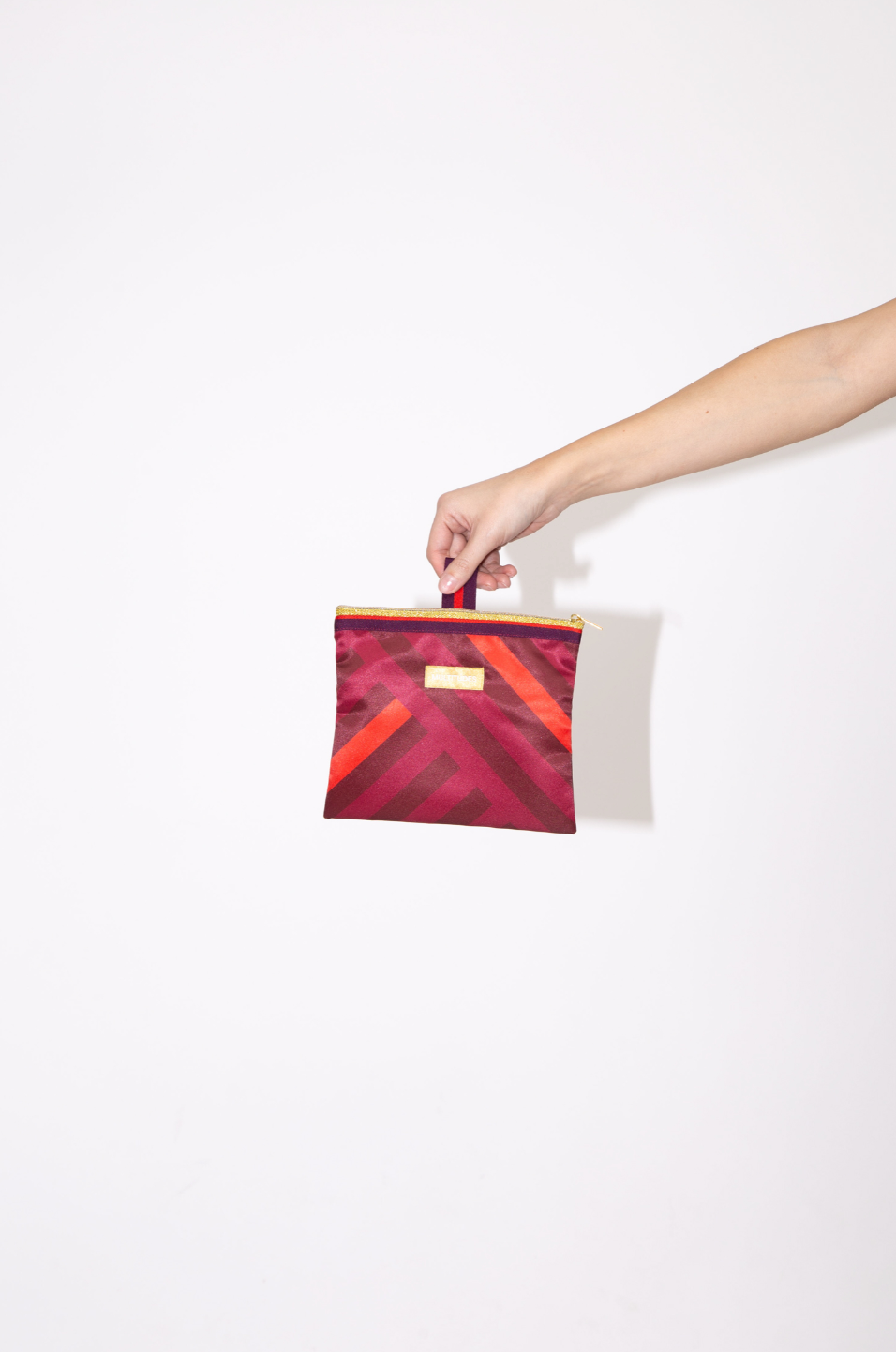 Pochette Stefania Purple de Multitudes, en violeta y naranja terracota, confeccionada en tejido reciclado efecto seda con cremallera dorada. Made in Italy.