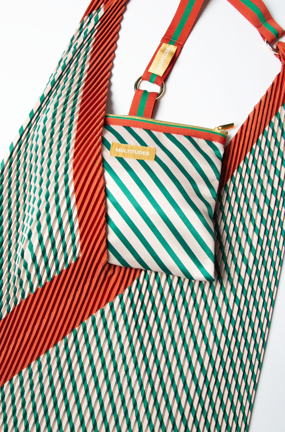 Pochette Francesca Green de Multitudes en verde botella y naranja, fabricada en tejido reciclado efecto seda, con cremallera dorada y lazo superior.