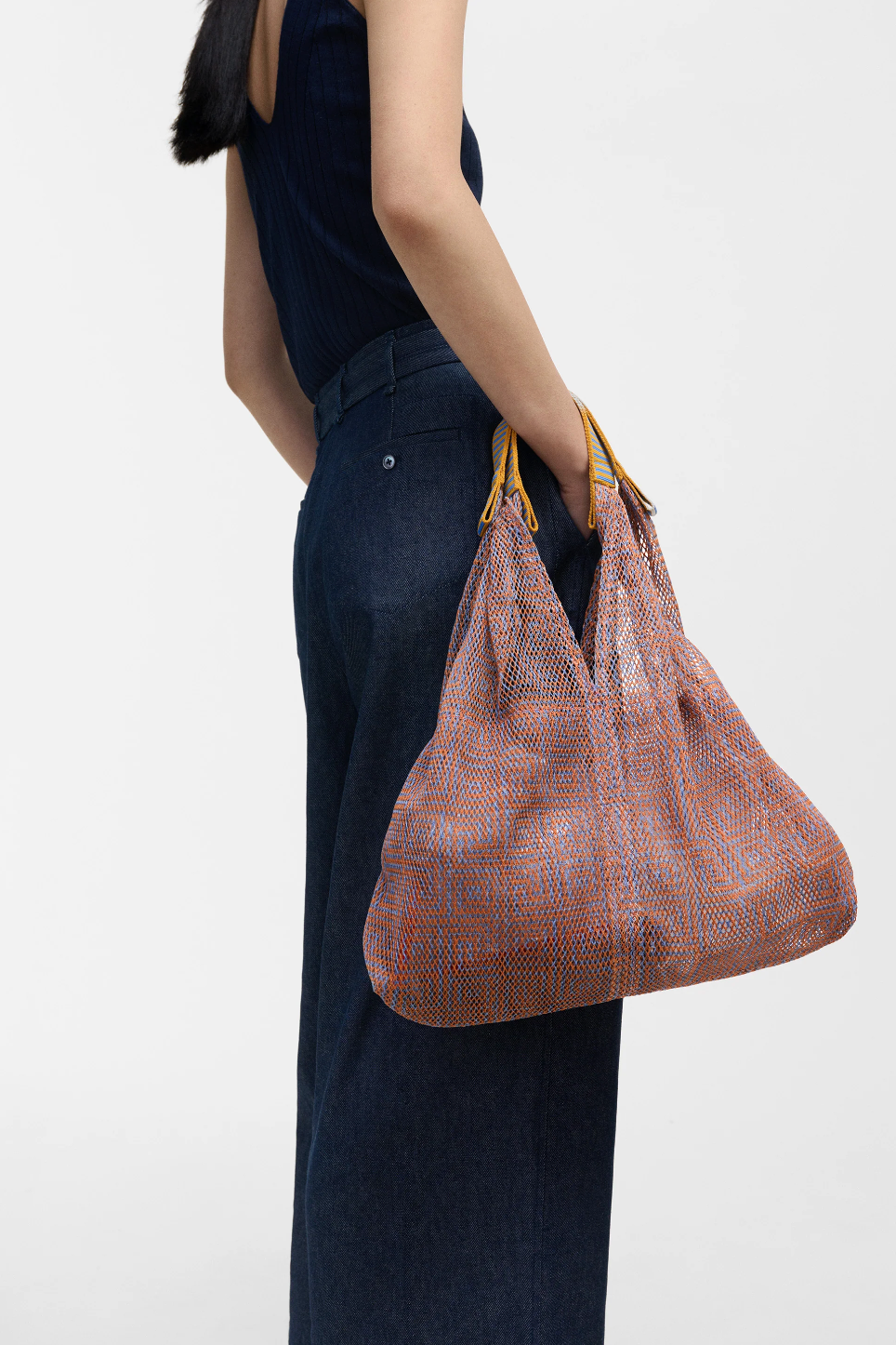 Small Udaipur Gold salmon pink geometric mesh tote bag carried on the arm by a model