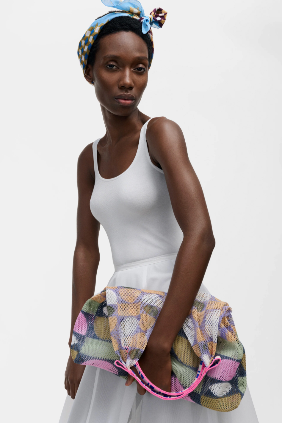 Small Udaipur Sage multicolor patchwork mesh tote bag with pink handles, held by a model, front view