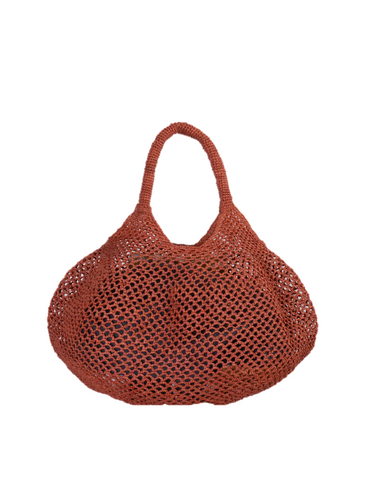 Cesta calada de rafia natural color teja de Sans-Arcident, bolso artesanal hecho a mano en Madagascar, ideal como bolso de verano o complemento sostenible para looks casuales.