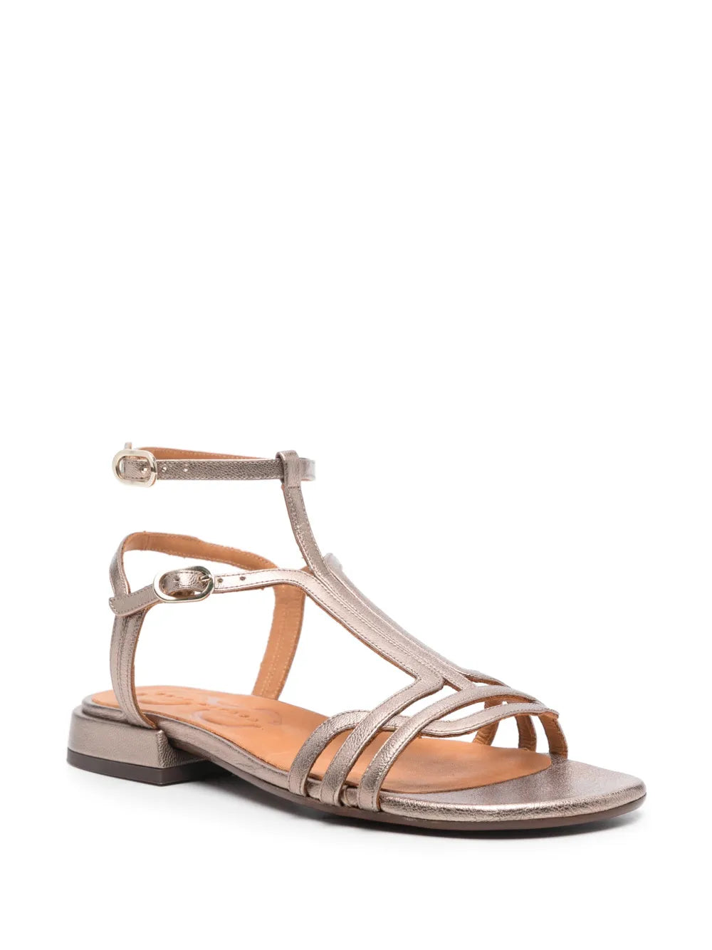 Sandalia plana Chie Mihara TYAL en piel plateada con cierre doble al tobillo y hebilla lateral. Con puntera abierta y tacón de 3 cm, es el calzado perfecto para un look cómodo y elegante. Fabricada en España, ideal para cualquier ocasión.