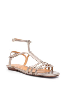 Sandalia plana Chie Mihara YAEL en piel plateada con cierre doble al tobillo, hebilla lateral y puntera abierta. Suela plana de cuero y goma, diseño cómodo y elegante.