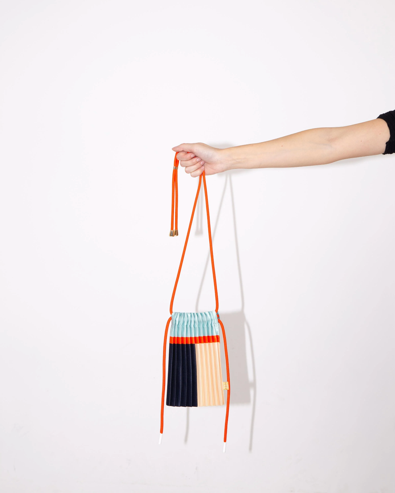 Multitudes pleated mini bag blue multicolor held by hand side view
