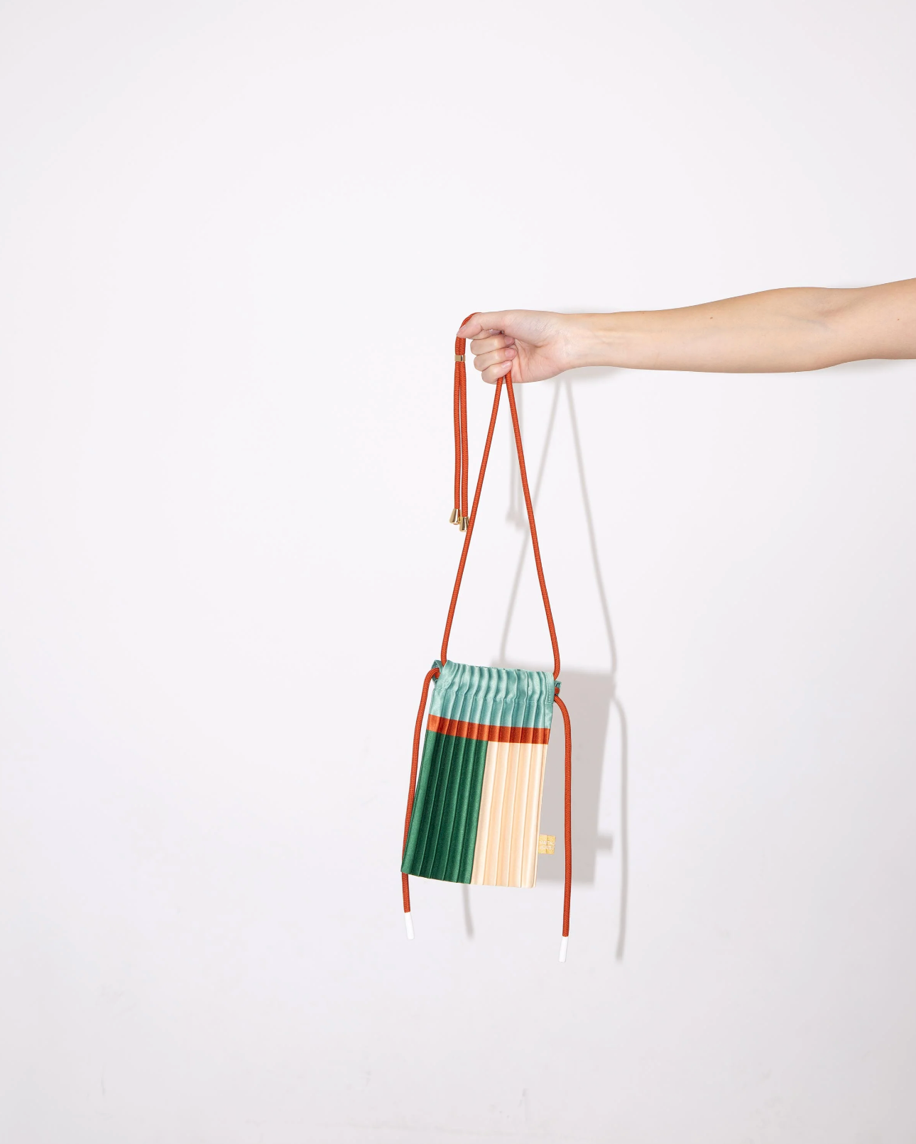 Multitudes pleated mini bag Esmerald green mint terracotta held by hand side view