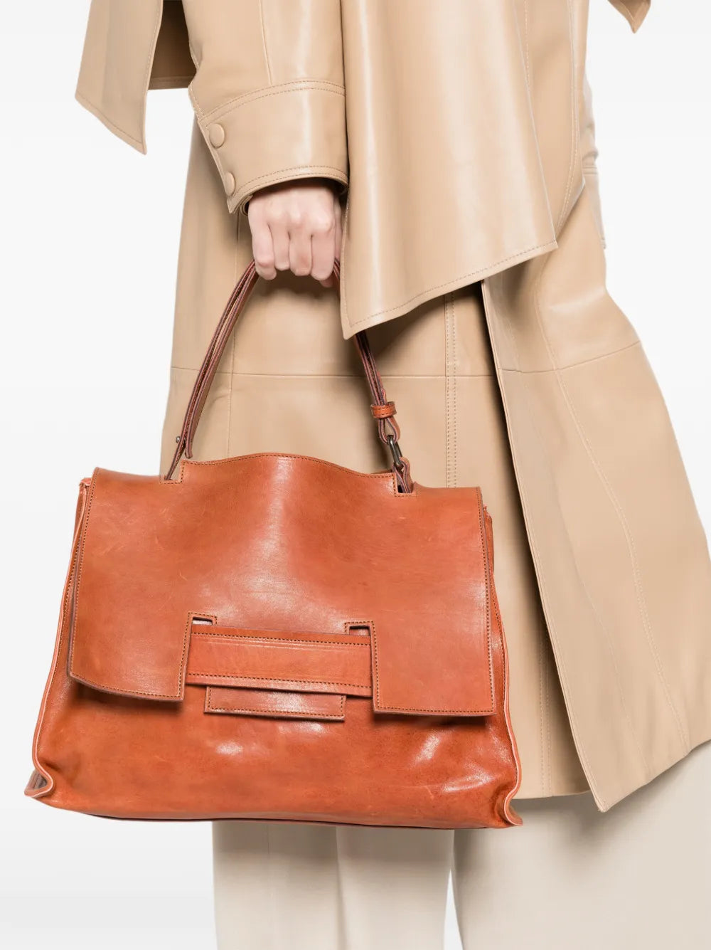 Sommet Mayway Little siena leather handbag carried by hand, structured silhouette with geometric flap detail, handcrafted in Italy.