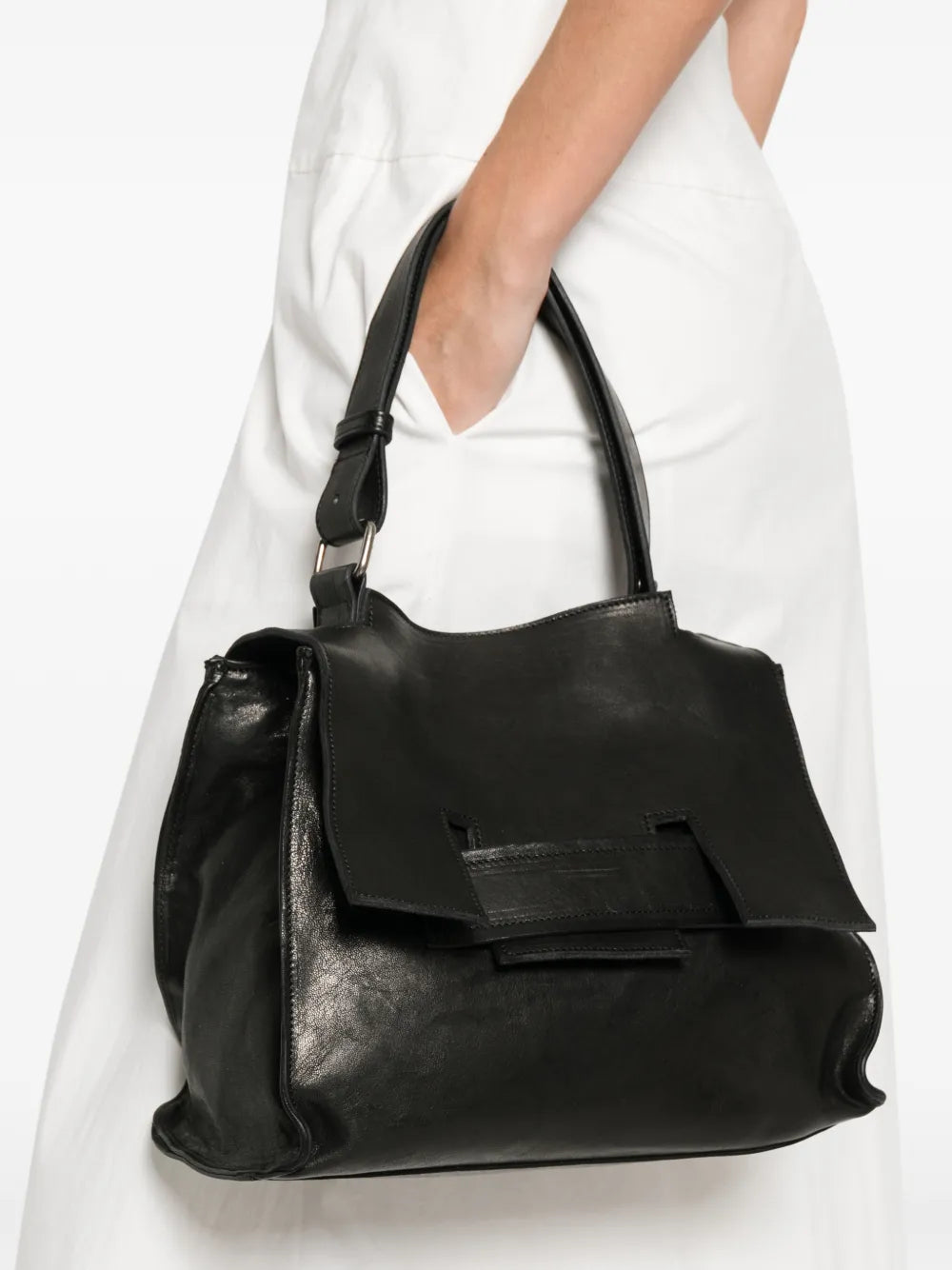 Black structured leather handbag with geometric flap and adjustable strap, handcrafted in Italy.