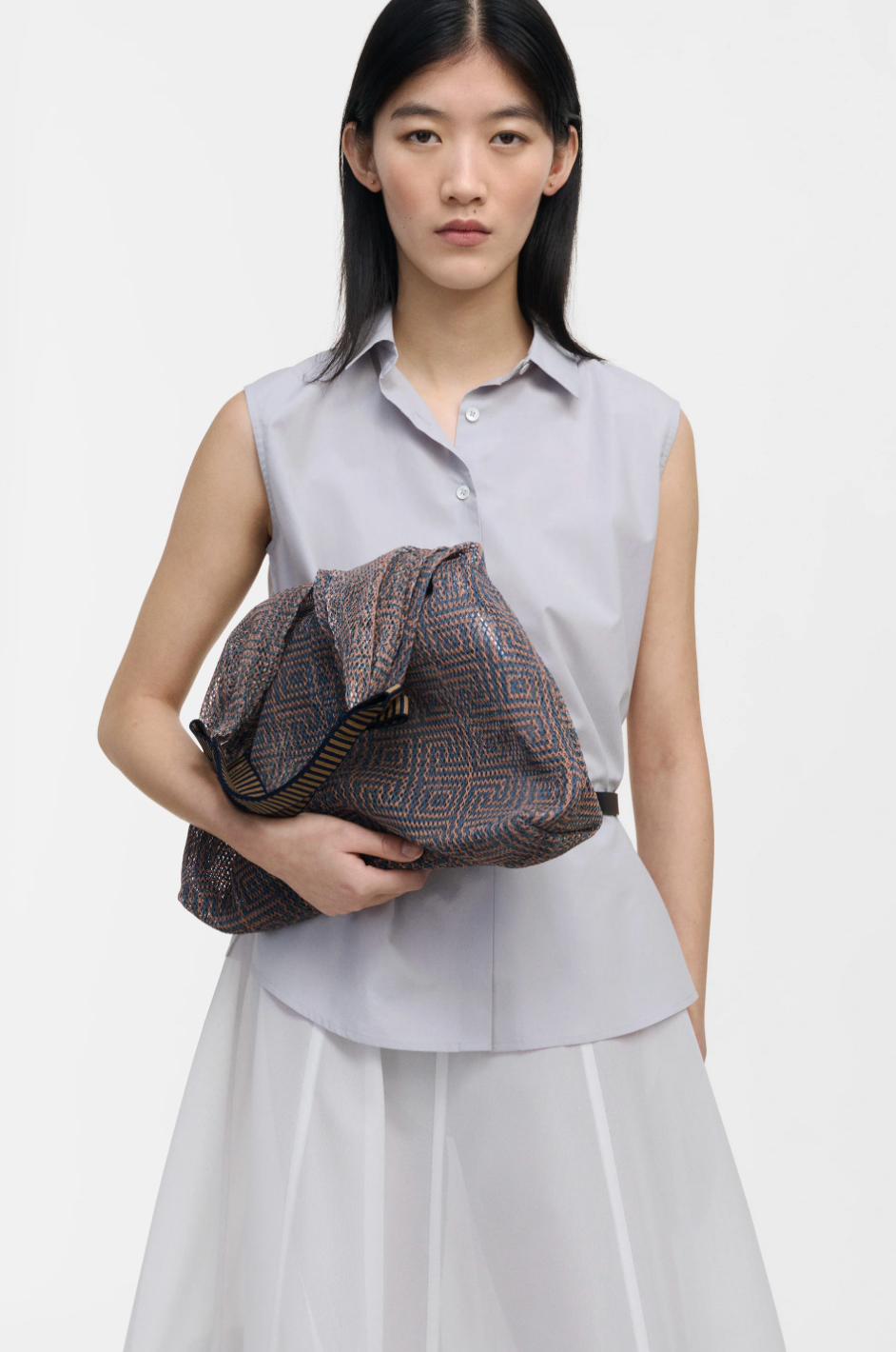 Small Udaipur Rosso dark grey geometric woven mesh tote bag carried by a model, styled with a light grey outfit
